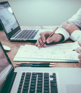 Person reviewing notes and a laptop at a desk